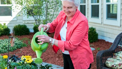 A resident watering flowers in a garden