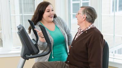 Staff member engaging with a resident in a fitness area