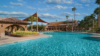 Outdoor pool area with shaded seating and landscaping