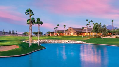 Exterior view of a facility beside a lake at sunset