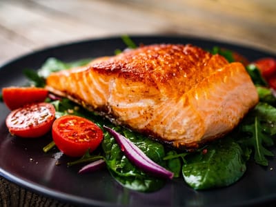 A plate of salmon with vegetables and tomatoes