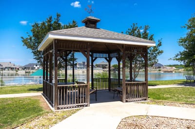 Outdoor gazebo by the lake in a park-like setting.