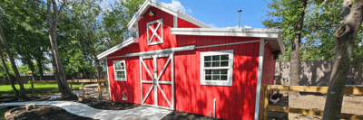 Exterior of a red barn structure in a garden
