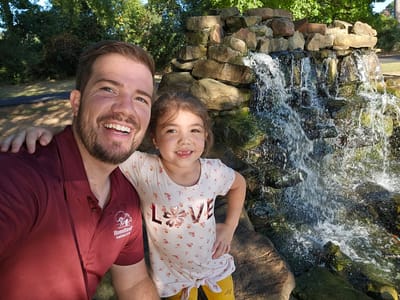 A man and girl next to a waterfall feature.
