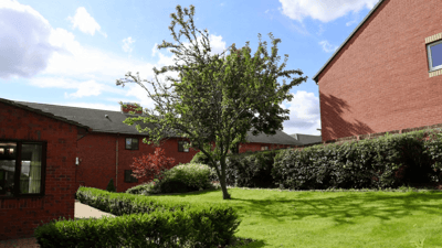 Outdoor area with trees and brick buildings.