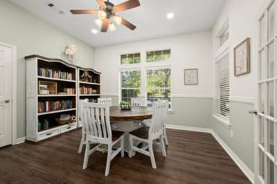 Bright common area with a wooden dining table and bookshelves.