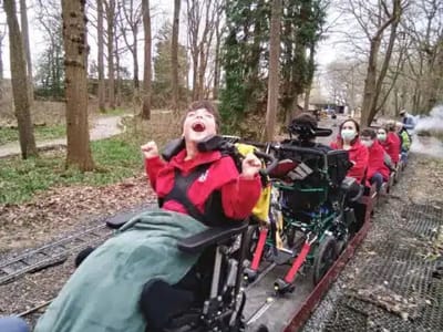 Residents enjoying a train ride outdoors in wheelchairs.