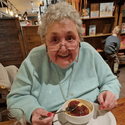 Elderly woman enjoying dessert at a table