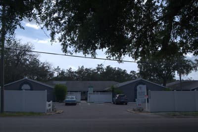 Exterior view of Inspired Living Tampa with trees and signage