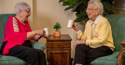 Two residents enjoying drinks and laughter together.