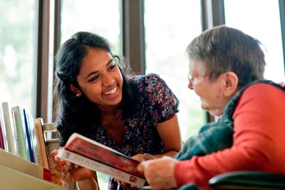 A caregiver reading with an elderly resident.