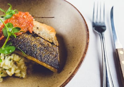 Plated salmon with risotto and tomato topping