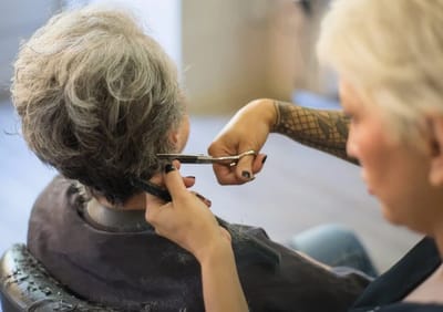 A hairstylist cutting a resident's hair.