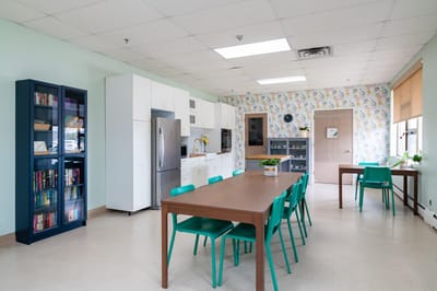 Bright communal dining area with green chairs.
