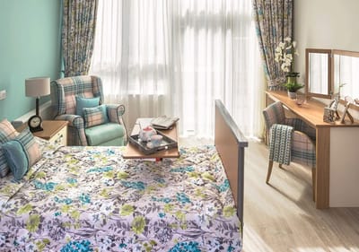 Cozy private resident room with floral bedding and natural light.