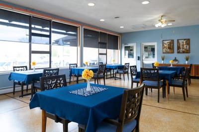 Bright dining area with tables and flowers.