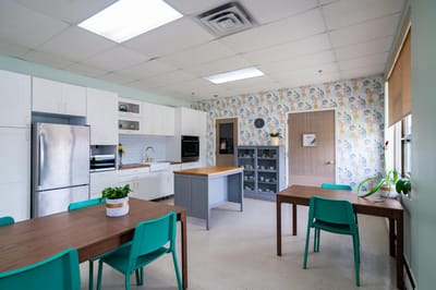 Bright communal kitchen with floral wallpaper and tables.