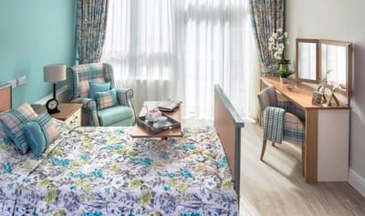 Bright resident bedroom with floral bedding and vanity.