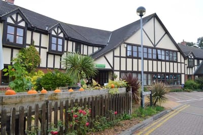 Exterior view of a senior care facility with gardens.