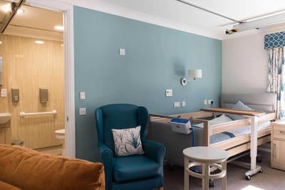 Cozy resident room with a hospital bed and chair.