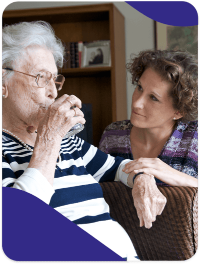Senior woman enjoying a drink with caregiver