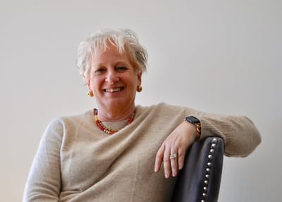Smiling woman seated in a cozy setting.