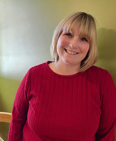 Senior staff member smiling in a red sweater