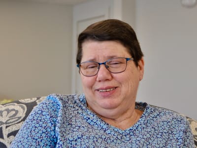 Resident smiling in a comfortable indoor setting.