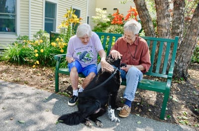 Two residents enjoying time with a dog outdoors