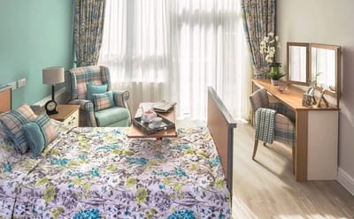 Cozy resident room with floral bedding and bright decor.