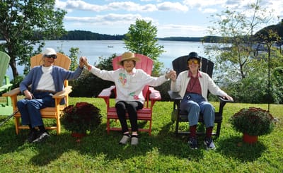 Three seniors enjoying a scenic view in colorful chairs.