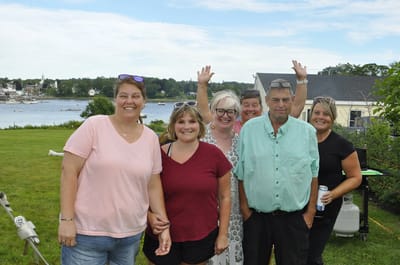 Group of smiling people outdoors by the water.