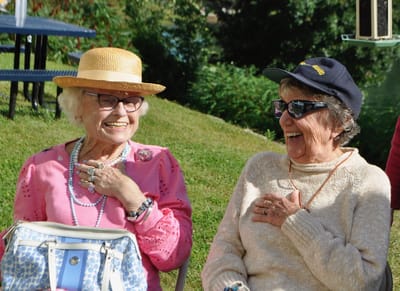 Two elderly women laughing outdoors.