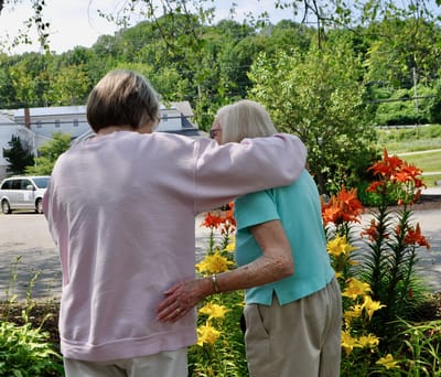 Two residents enjoying flowers in the garden.