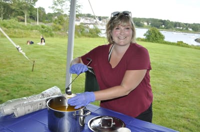 Staff member serving food outdoors at an event.