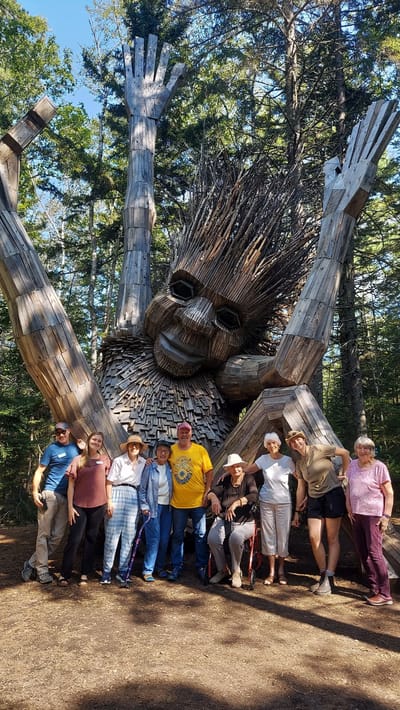 Group of residents with a large wooden sculpture.