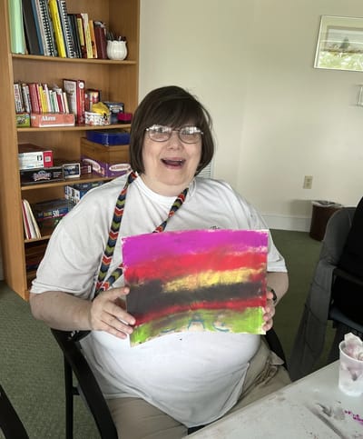 Resident holding a colorful painting during an activity.