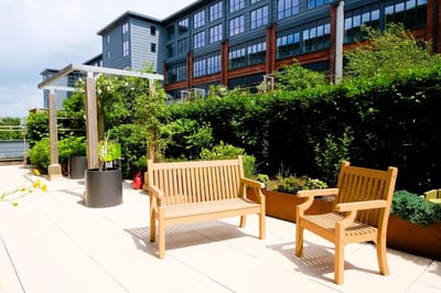 Outdoor seating area with benches and greenery.