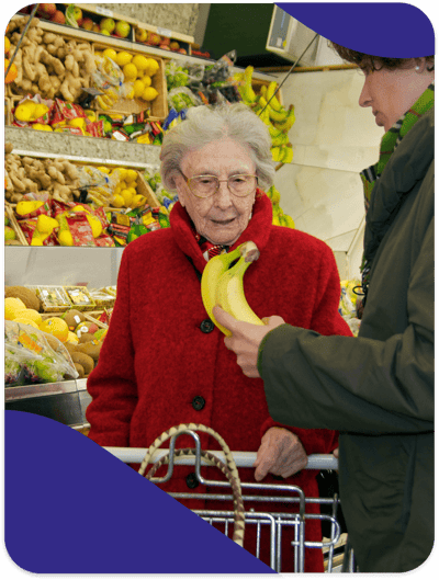 Elderly woman choosing bananas in a market.