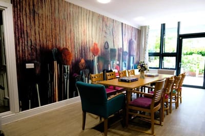 Bright common area with colorful chairs and art wall.