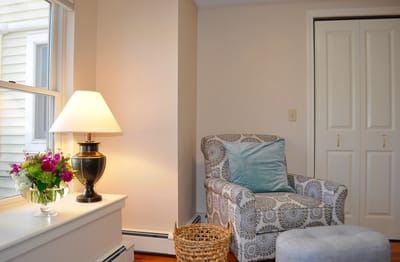 A cozy chair and lamp in a well-lit room.