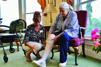 Staff member assisting a resident with leg elevation.