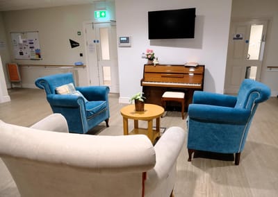 Comfortable seating area with a piano in the background.