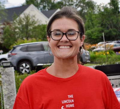 Staff member smiling outdoors at a community event.