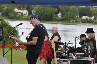 A band performing outdoors by the waterfront.