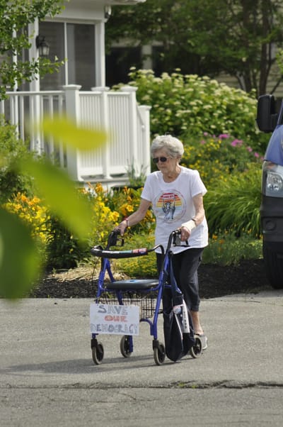 Senior resident walking with a walker in the garden.