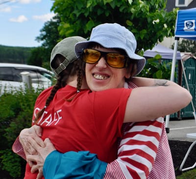 Two women embracing outdoors at an event.