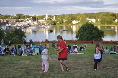 Children playing on the lawn near a waterfront event