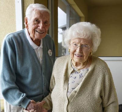 Two smiling residents holding hands.
