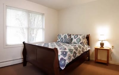 Bright interior of a resident room with a bed and lamp
